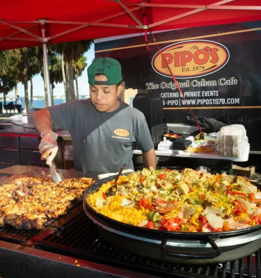 a young man cooking Cuban food at the Shopapalooza event, outdoors in Vinoy Park