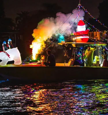 a boat lit up for a holiday parade with a blow-up polar bear in the bow and an American flag at the stern