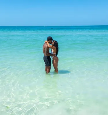 a couple kissing while standing in clear turquoise waters at the beach