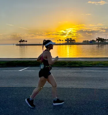 two runners at sunrise near the water and the St. Pete Pier