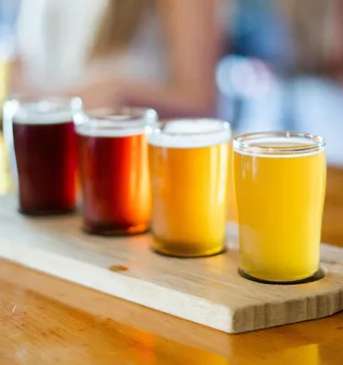 A flight of four tiny glasses of beer in different shades inside a brewery in Florida.