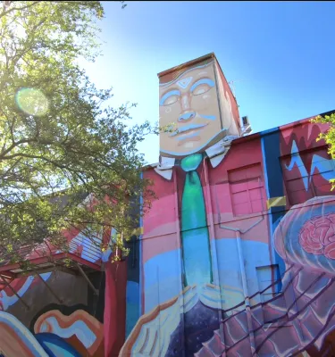 A colorful mural of a man in a suit painted on a wall of a tall building in Florida.