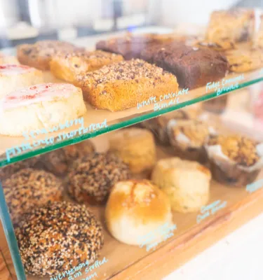 Bakery display of colorful pastry like shortbread, muffins, blondies and stuffed buns at Grove Coffee in Florida.
