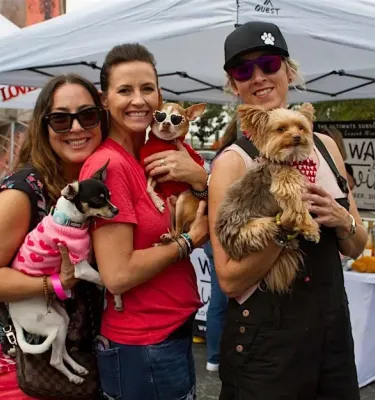 Women holding dogs at a rescue event outside.
