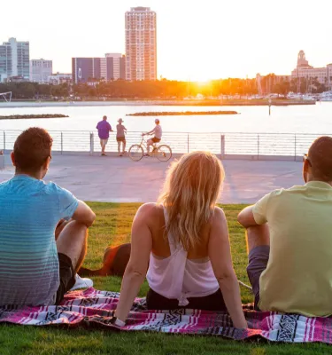 Three people on a blanket looking out over the water at the St. Pete Pier