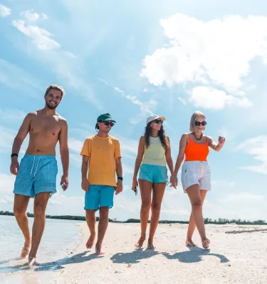 four adults walk on a beach at Shell Key
