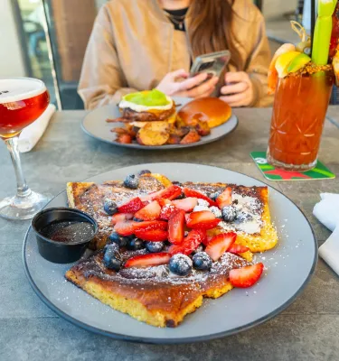 pancakes with berries on top near a bloody Mary and other breakfast items at Clear Sky Beachside Cafe