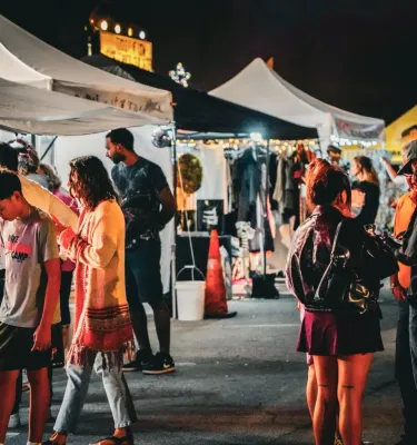 St. Pete Night Market featuring people shopping around vendor tents at night. 