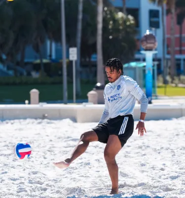 A guy playing volleyball with his foot