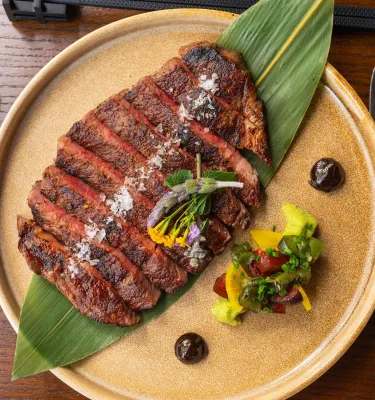 a plate of skirt steak sliced and served rare atop a large green leaf at Fortu in St. Petersburg FL