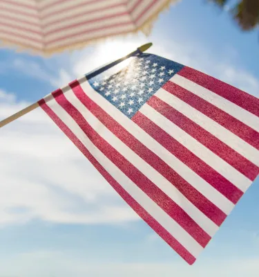 someone holding an American flag at the beach