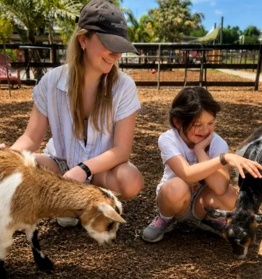 A woman and girl pet two playful goats at DK Farms & Gardens in Largo, Florida