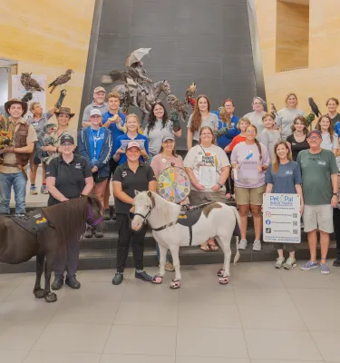 Group of kids and adults inside a museum event hosted with animals.