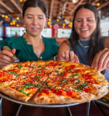 two women get ready to dig into a margarita pizza at Nona Slice House in Safety Harbor