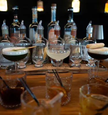 Assorted craft cocktails displayed in front of spirit bottles at St. Pete Distillery.