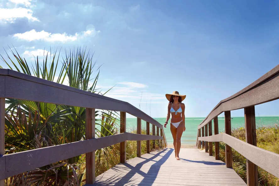 Una joven vestida en bikini caminando por el paseo marítimo de Indian Rocks Beach.
