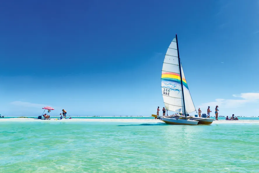 A Catamaran sailboat anchored under blue sky in the emerald-green waters of Outback Key near Fort de Soto.