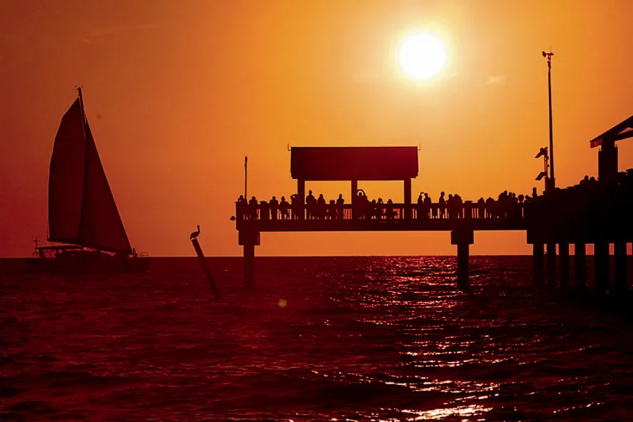 Pier 60 ao pôr do sol com um barco à vela na água