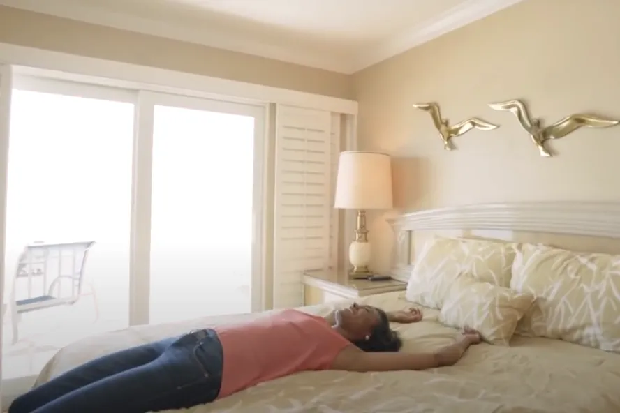A woman lays on the bed of a JC Vacation Rental