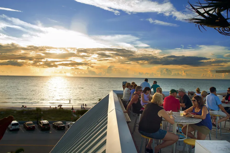 People dining on the rooftop of a rooftop bar at sunset