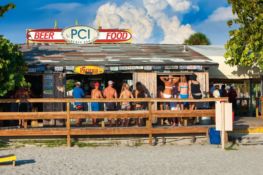 Exterior shot of people drinking at Postcard Inn Beach Bar & Snack Shack in St. Pete Beach
