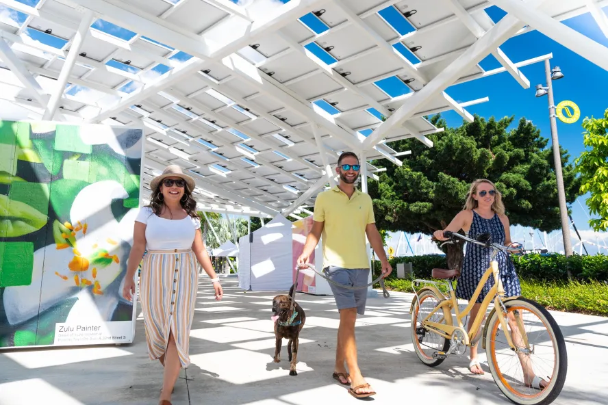 Three people and a dog stroll down the St. Pete Pier Marketplace