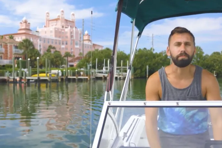 A man riding a boat off of intracoastal waters of St. Pete. Vinoy Resort can be seen at a distance.