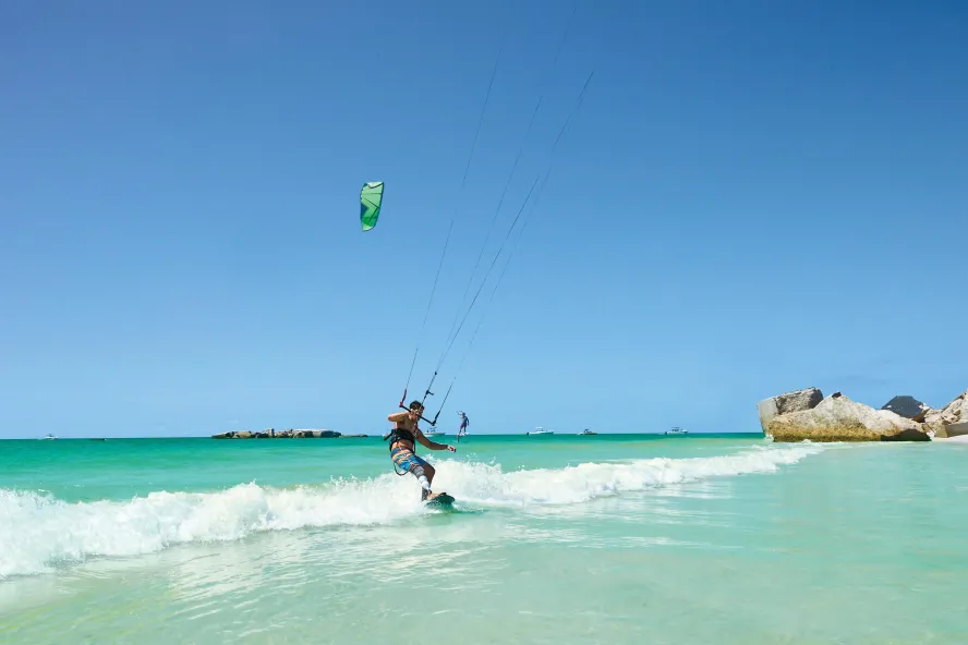 Ein Mann beim Kitesurfen vor Egmont Key. Das Wasser ist smaragdgrün mit kleinen Wellen und die Ruinen von Fort Dade sind zu sehen.