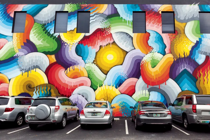 Several cars parked in front of a colorful mural