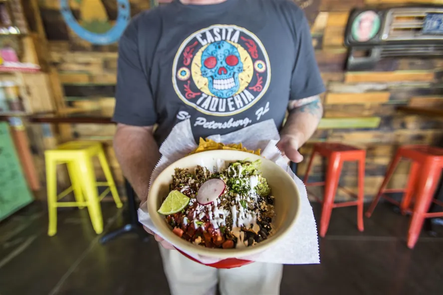 A waiter holds up a taco bowl from Casita Taqueria in downtown St. Pete