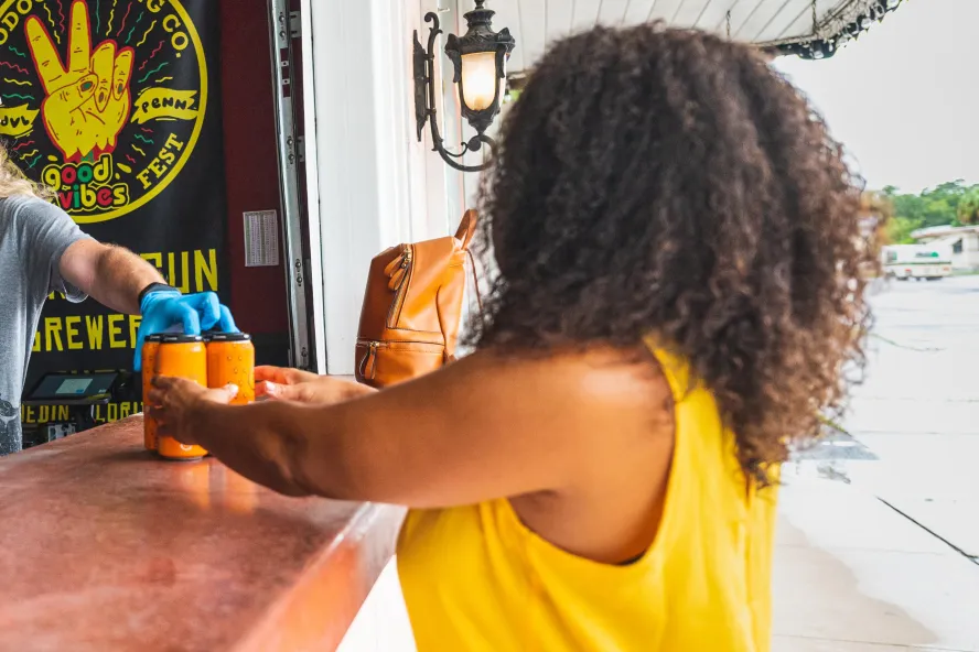 A woman grabs some to go beers from Seventh Sun Brewery in Dunedin
