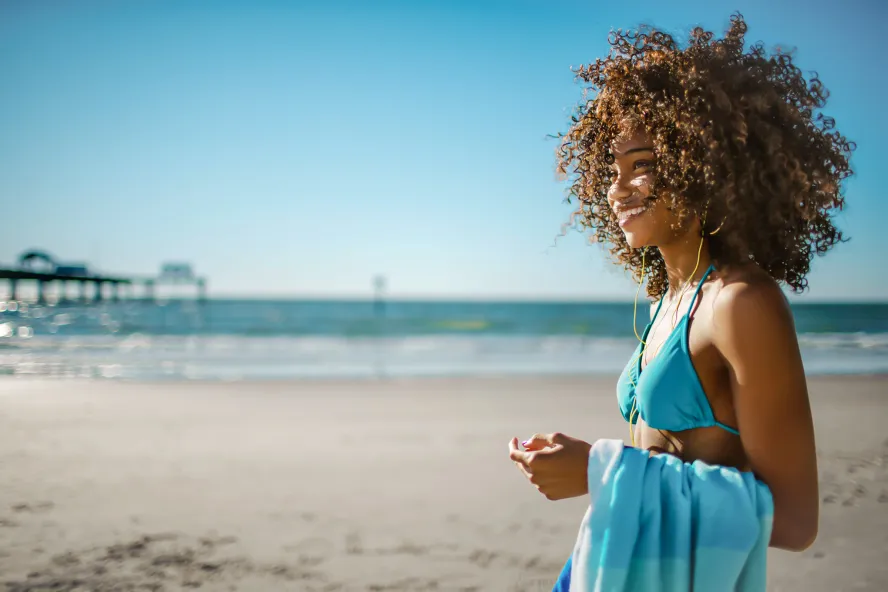 Uma mulher em Clearwater Beach se levanta e sorri longe da câmera com o Pier 60 ao fundo