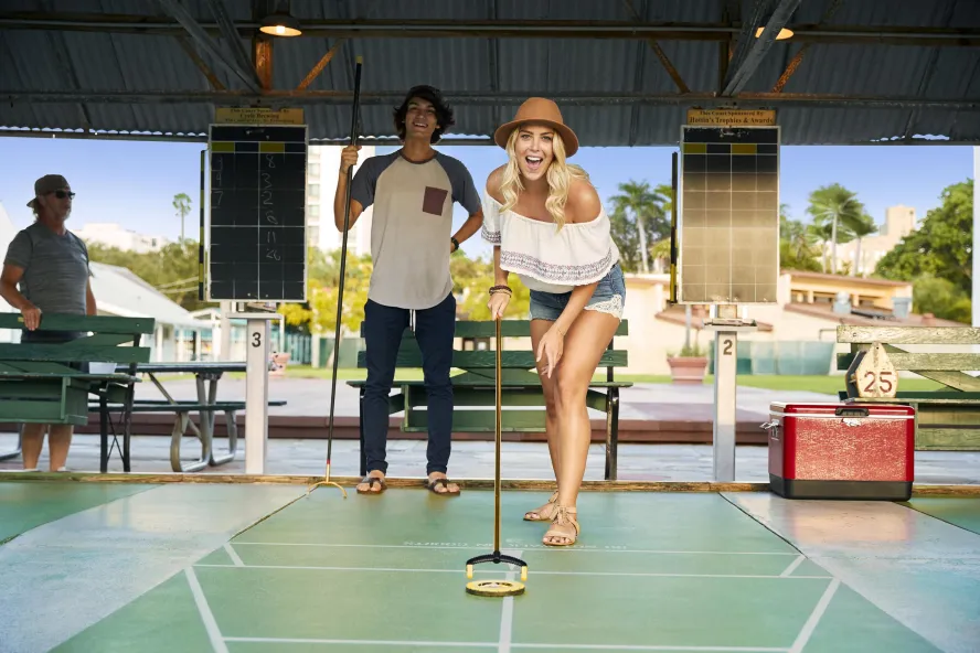 A woman pushes a disc on a shuffleboard at the St. Pete Shuffleboard Club
