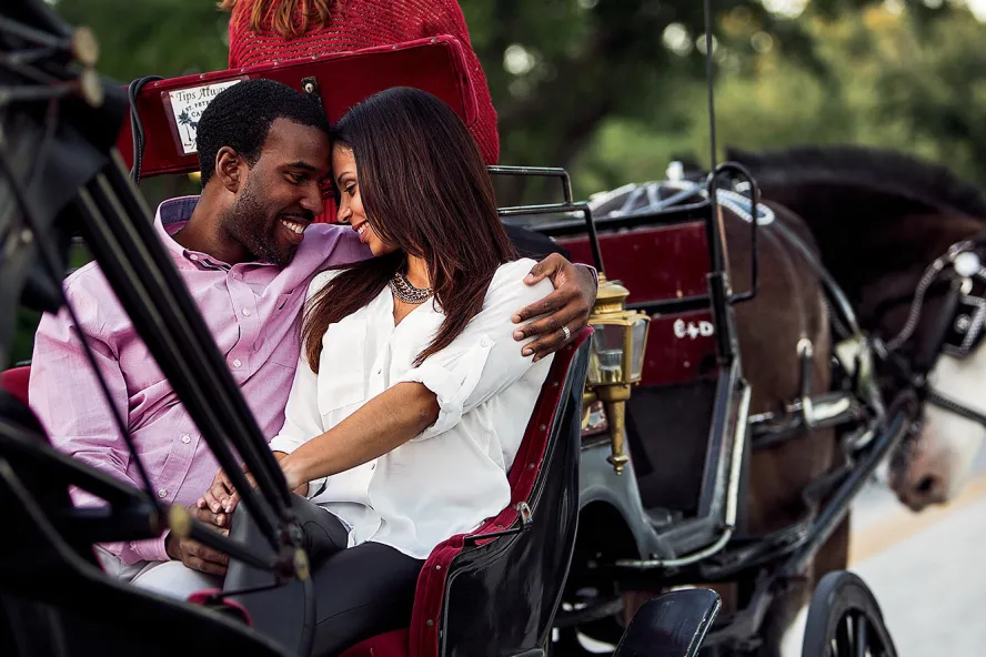 An African-American couple looking closely to each other while riding a carriage.