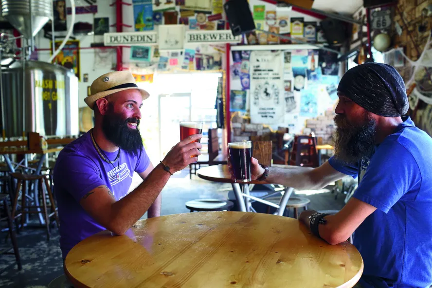 Two man toasting with beer inside of Dunedin Brewery.