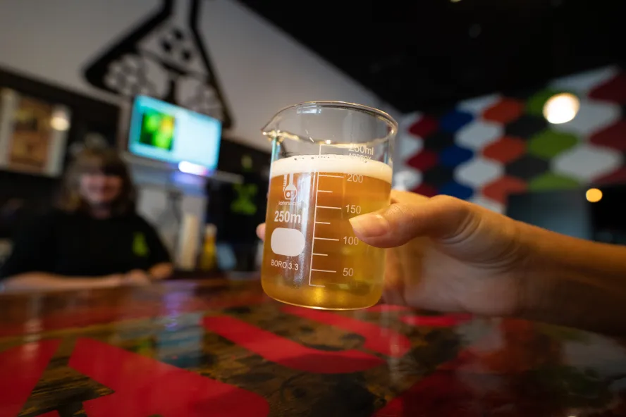 A person showing a lab glass with beer.