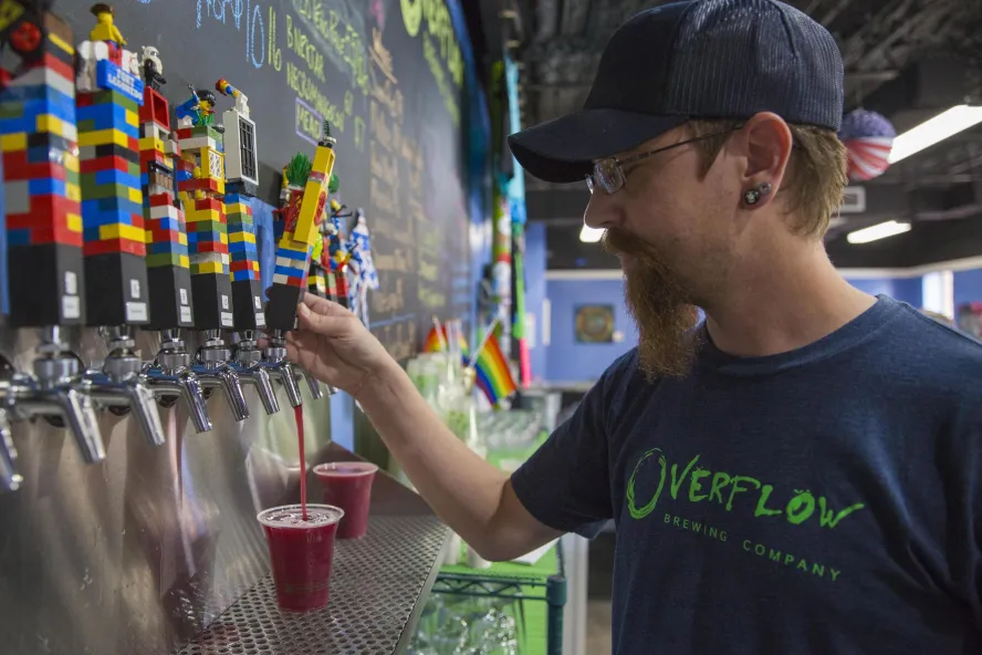 A man pouring a red beer from the Lego-looking beer taps.