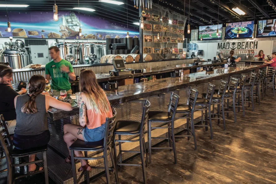A few people sit at the bar at Mad Beach Brewing.