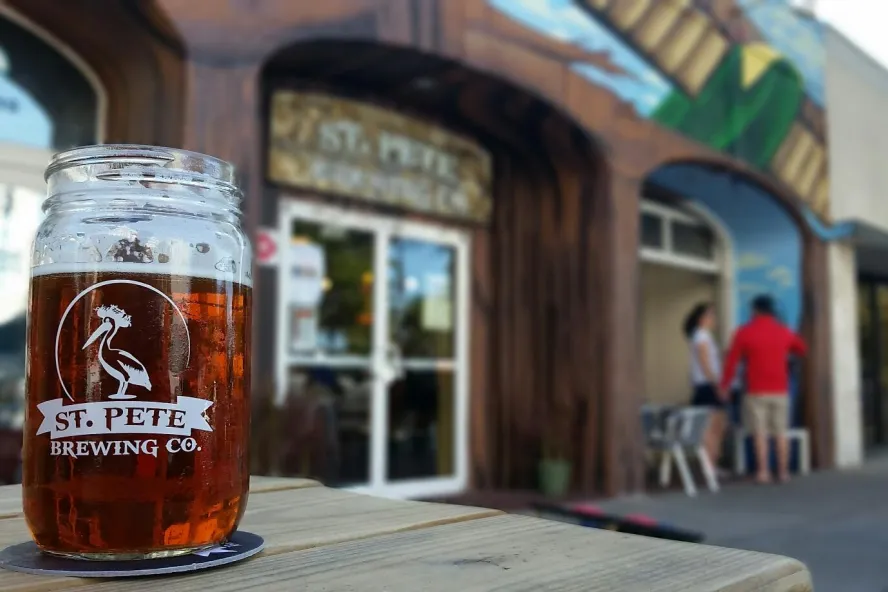 A beer glass on top of a table outside of St. Pete Brewing Co.
