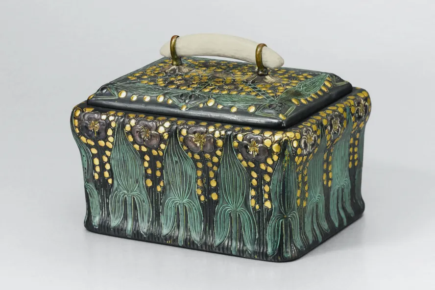 A small black ceramic box that is hand-painted with green and gold accents.