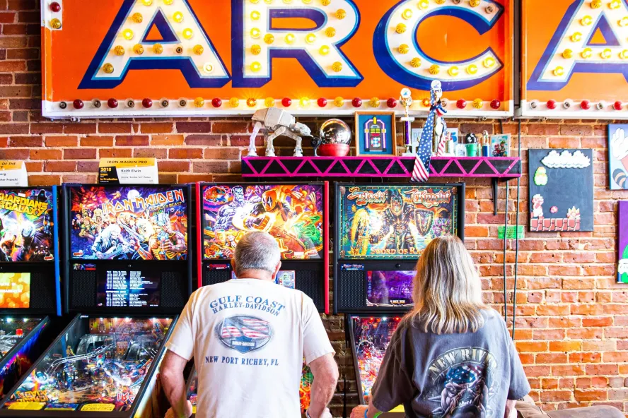 Two people play pin ball at the Replay Museum