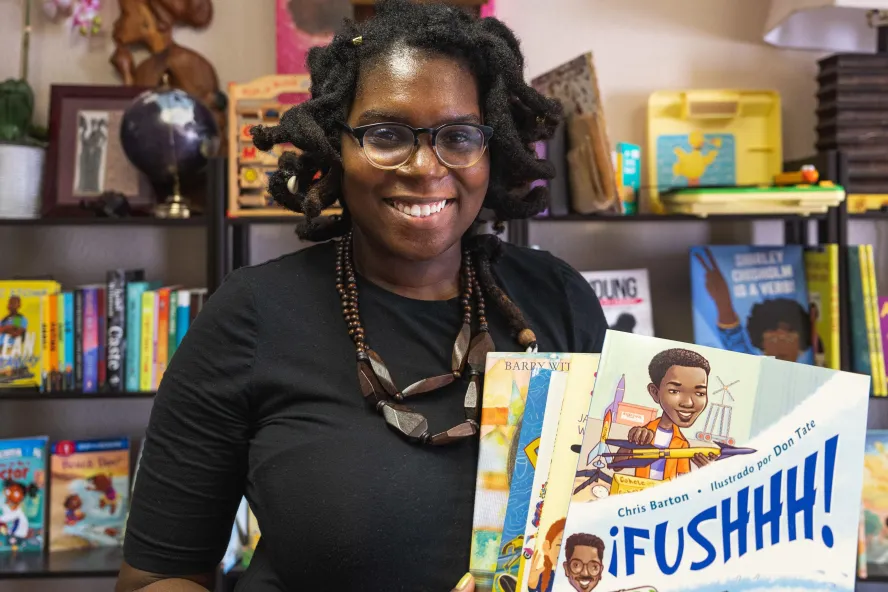 A woman holds up a book from the book store she owns.