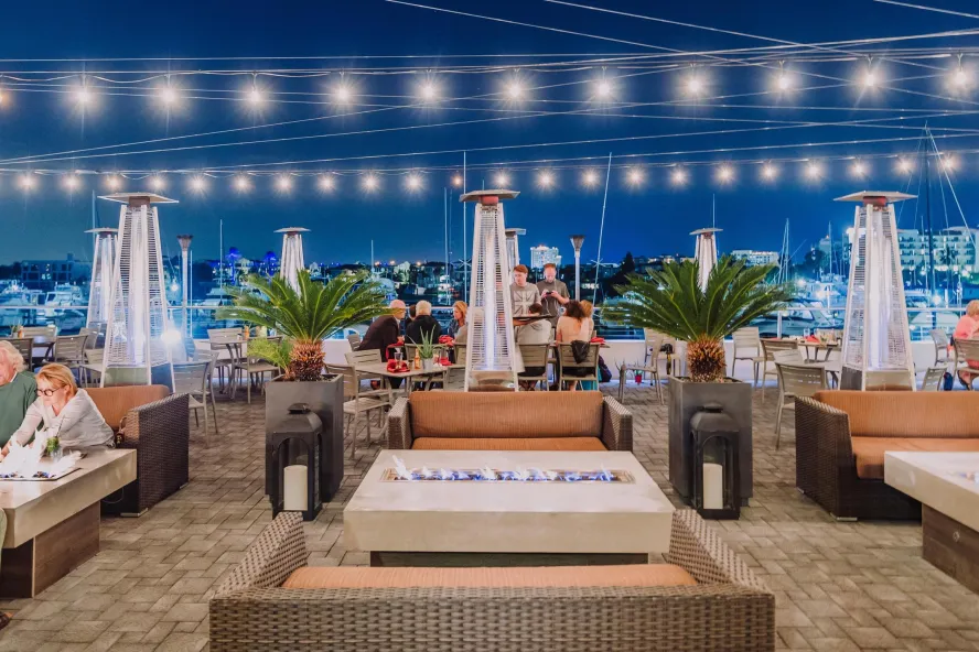 Image of outside dining area at Marina Cantina restaurant in Clearwater, FL. Featuring string lights and cushy seating for comfortable al-fresco dining.