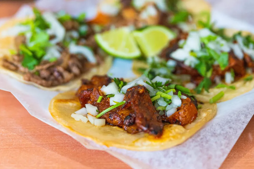 a plate of al pastor tacos with lime slices at El Huarache Veloz in Pinellas Park