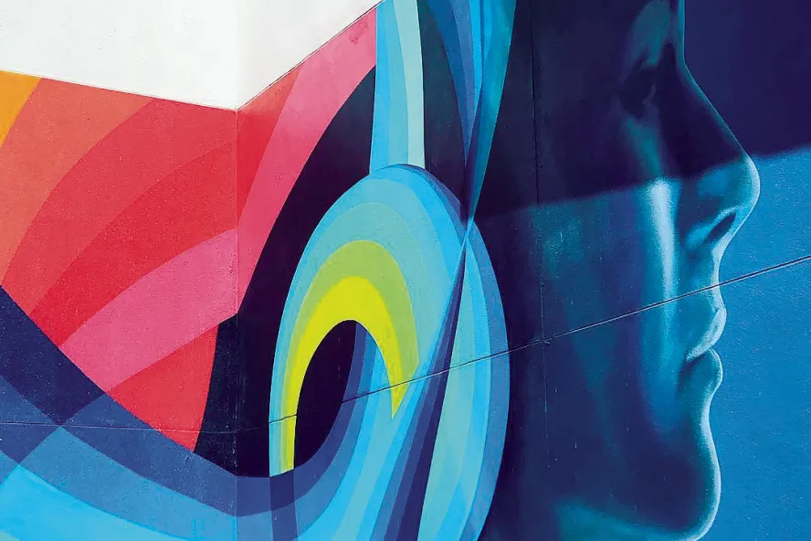 a mural depicts the side of a woman's face in medium and deep blue colors; her hair is rainbow colored and curled