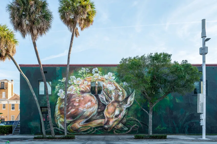 A building with a mural of a sleeping fawn on its walls.