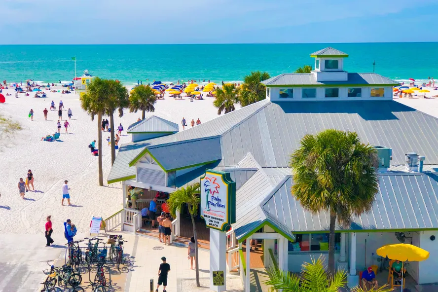 Outside of the Crabby's Beachside Pavilion restaurant on Clearwater beach with people walking around outside featuring blue ocean water.