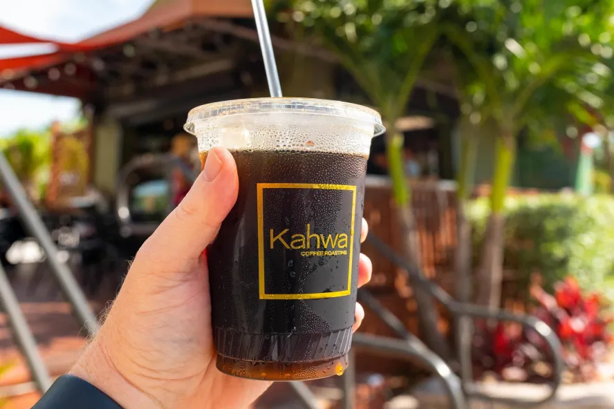 Hand holding a cup of iced coffee with Kahwa logo on it