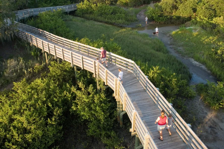 A wooden boardwalk with a few people walking through Boca Ciega Millennium Park