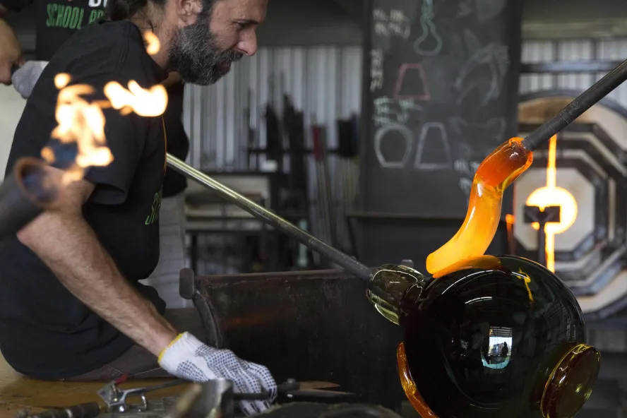A man works with molten glass at the DMG School Project